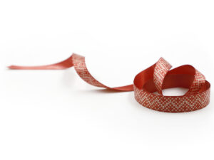 Elegant red ribbon with small white geometric pattern. Double-sided ribbon, ideal for B2B holiday decorations. Manufacturer AMGS Group.