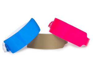 Wide vinyl wristbands (25mm) in blue, gold, and pink. Premium VIP access bands suitable for custom branding. Manufacturer AMGS Group.